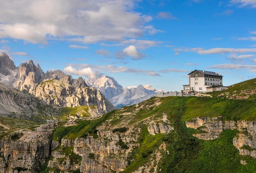 Immagine con rifugio, nuvole, erba, cielo, montagna, montagne, verde, tetto, azzurro, roccia, cime, finestre, bianco, rocce, panorama, edificio