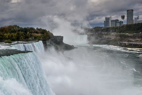 Immagine con acqua, nuvole, cascata, fiume, alberi, grattacieli, niagara, cascate, spruzzi