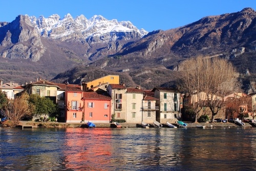 Immagine con montagne, neve, case, barche, alberi, fiume, montagna, lago, acqua, borgo, cielo