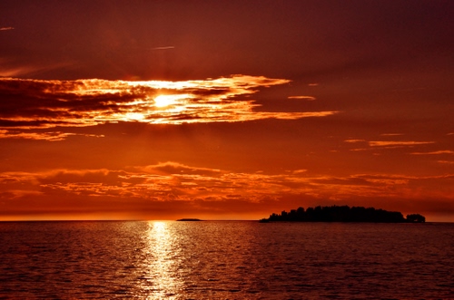 Immagine con mare, nuvole, isola, tramonto, rosso, acqua, arancione, riflessi, arancio, sole