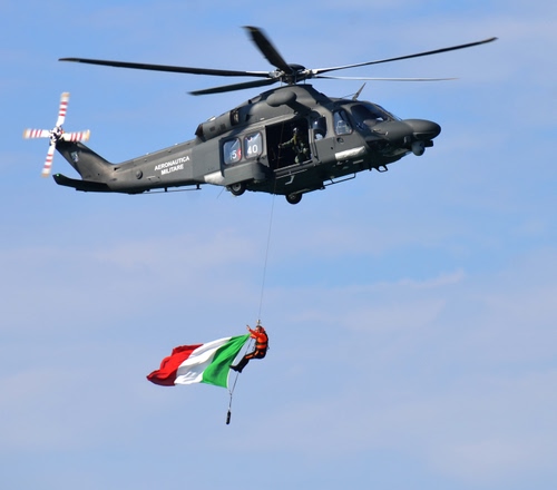 Immagine con bandiera, elicottero, pale, tricolore, verde, cielo, rosso, bianco, militare, eliche, uomo, aeronautica, persona, fune