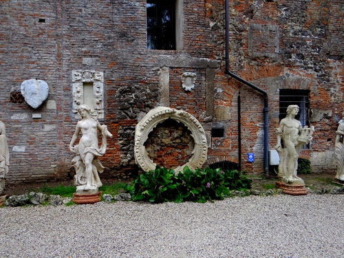 Immagine con statue, cerchio, muro, mattoni, ghiaia, piante, erba, sculture, finestra, marmo, finestre, verde, foglie, grondaia, stemmi, archeologia
