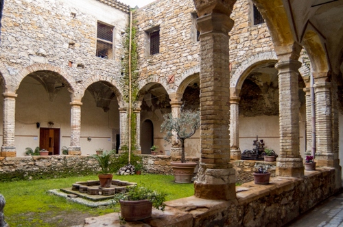 Immagine con archi, colonne, chiostro, vasi, piante, verde, erba, pilastri, finestre, capitelli, arco, giardino, portico, mattoni, cortile, sassi, mura, edera, pietra, convento, colonna, fiori