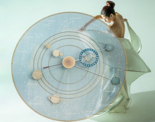 Immagine con donna, orologio, lancette, cerchi, pianeti, ballerina, vestito, zodiaco, velo, cerchio, bianco, azzurro, trasparenze, braccio, ballo, danza, ragazza